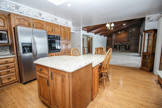 kitchen featuring appliances with stainless steel finishes, light wood-type flooring, wooden ceiling, vaulted ceiling with beams, and a kitchen island