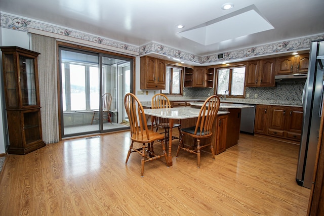 kitchen featuring a kitchen island, a skylight, stainless steel appliances, light hardwood / wood-style floors, and a kitchen breakfast bar