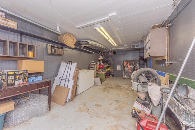 basement with fridge, an AC wall unit, and a workshop area