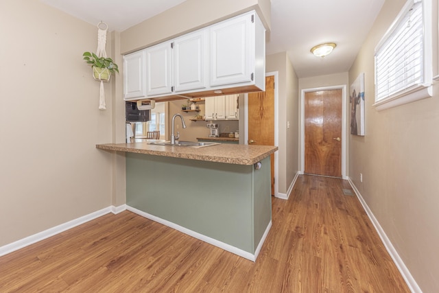 kitchen featuring kitchen peninsula, sink, white cabinetry, and light hardwood / wood-style flooring