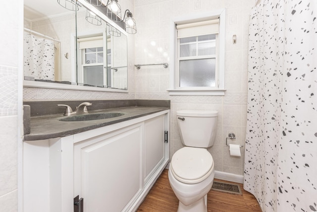 bathroom featuring toilet, hardwood / wood-style floors, tile walls, walk in shower, and vanity