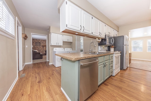 kitchen featuring white cabinetry, appliances with stainless steel finishes, independent washer and dryer, light hardwood / wood-style flooring, and sink