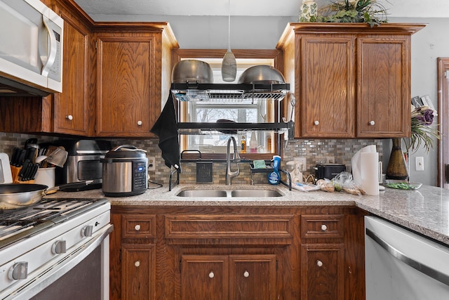 kitchen with sink, gas range gas stove, hanging light fixtures, decorative backsplash, and stainless steel dishwasher