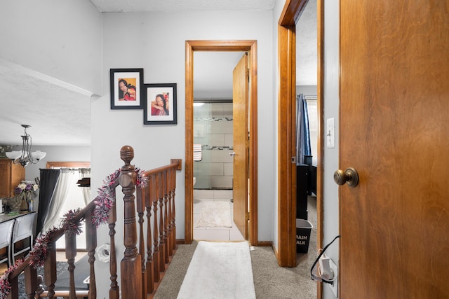 hall featuring a chandelier, light carpet, and a textured ceiling