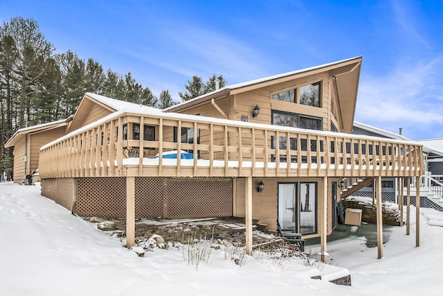 snow covered rear of property with a wooden deck