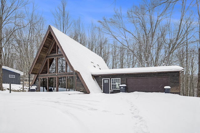 snow covered rear of property with a garage