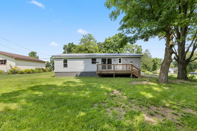 back of property featuring a deck and a lawn