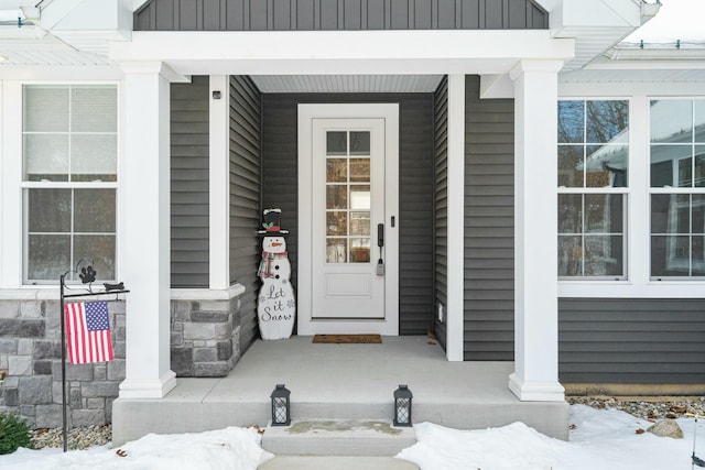 snow covered property entrance with a porch