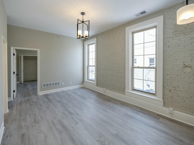 spare room with a notable chandelier and light hardwood / wood-style floors