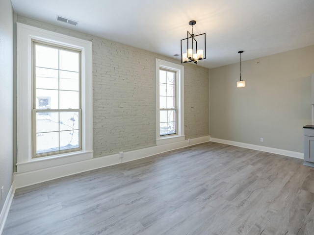 unfurnished dining area featuring an inviting chandelier and light hardwood / wood-style flooring