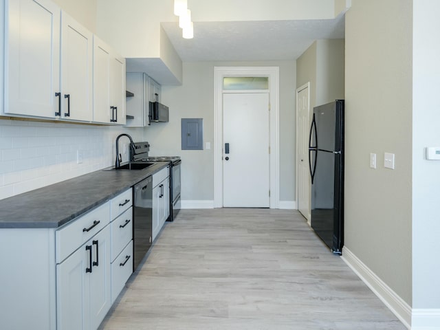 kitchen featuring sink, electric panel, black appliances, white cabinets, and decorative backsplash