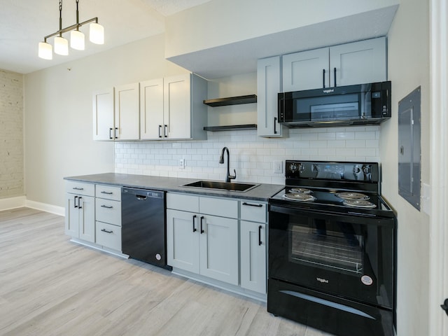 kitchen with tasteful backsplash, sink, white cabinets, black appliances, and light hardwood / wood-style flooring