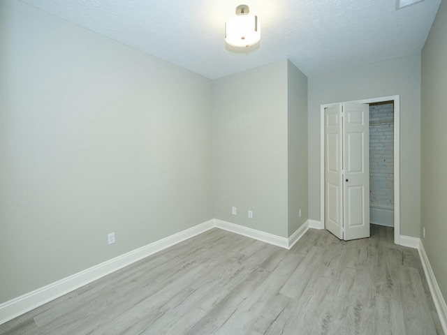 unfurnished bedroom with a closet, light hardwood / wood-style flooring, and a textured ceiling