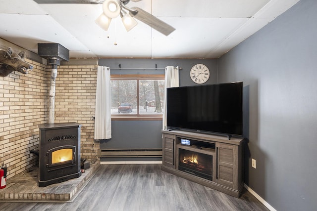 living room featuring ceiling fan, baseboard heating, a wood stove, and dark hardwood / wood-style flooring