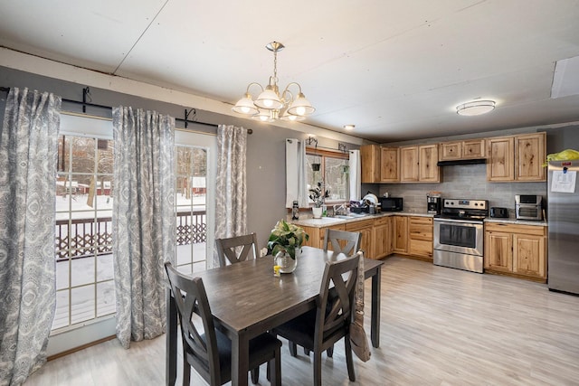 dining area with light wood-type flooring, an inviting chandelier, a wealth of natural light, and sink