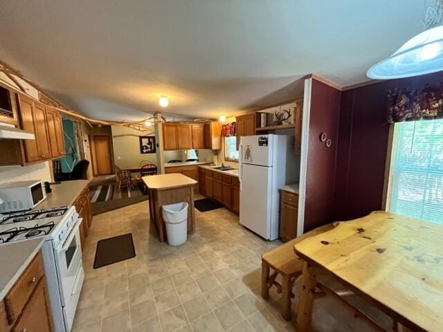 kitchen featuring a center island, hanging light fixtures, and white appliances