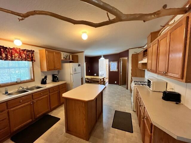 kitchen featuring a kitchen island, sink, hanging light fixtures, and white appliances