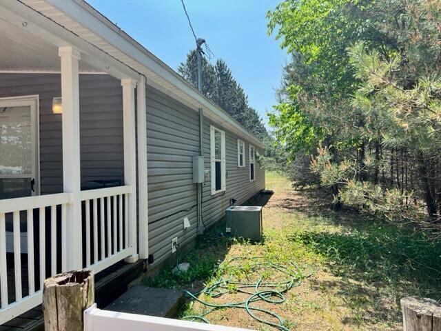 view of side of home with central AC and a yard