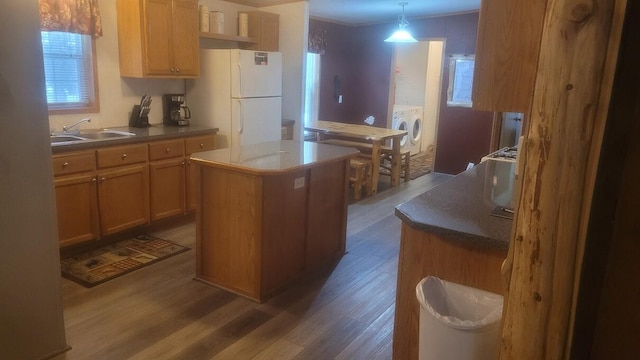 kitchen featuring a center island, dark wood-type flooring, white fridge, a healthy amount of sunlight, and sink