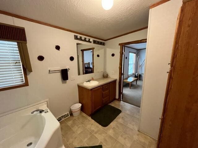 bathroom with vanity, a bath, a textured ceiling, and ornamental molding