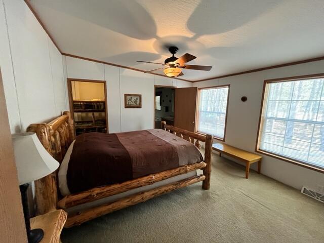 bedroom featuring ceiling fan, crown molding, and carpet floors