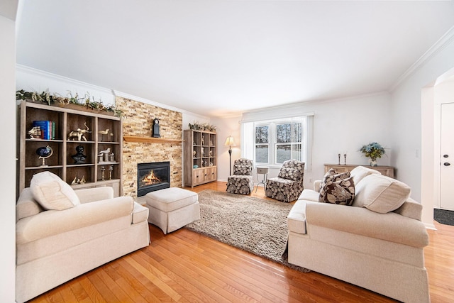 living room with wood-type flooring, ornamental molding, and a fireplace