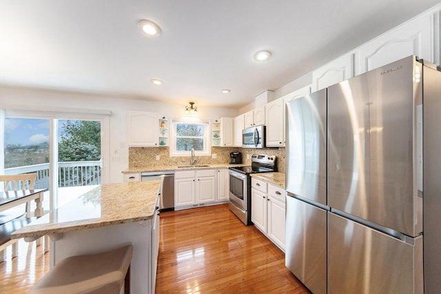 kitchen featuring sink, appliances with stainless steel finishes, backsplash, light stone counters, and white cabinets