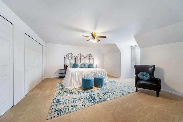 carpeted bedroom with ceiling fan, vaulted ceiling, and two closets