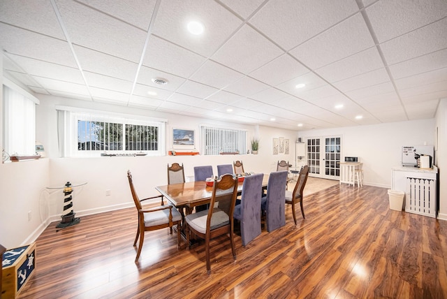 dining area with a drop ceiling and dark wood-type flooring