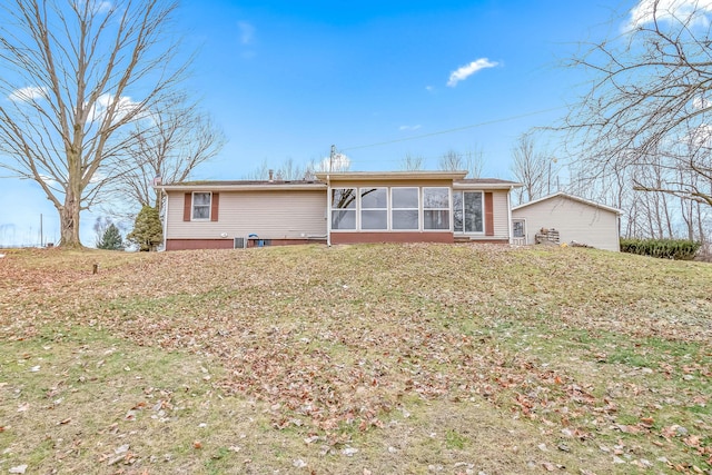 rear view of house featuring a lawn and a sunroom