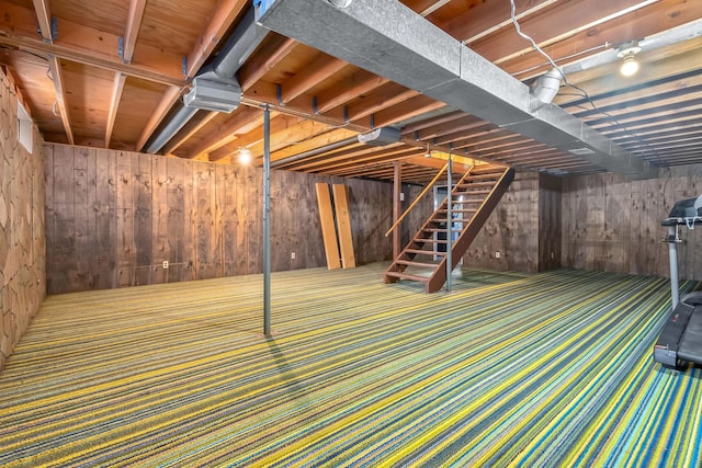 basement featuring carpet floors and wood walls