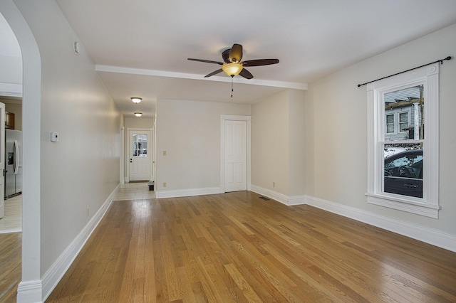 empty room featuring light wood-type flooring, a healthy amount of sunlight, and ceiling fan