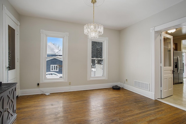 unfurnished dining area featuring dark hardwood / wood-style flooring and an inviting chandelier