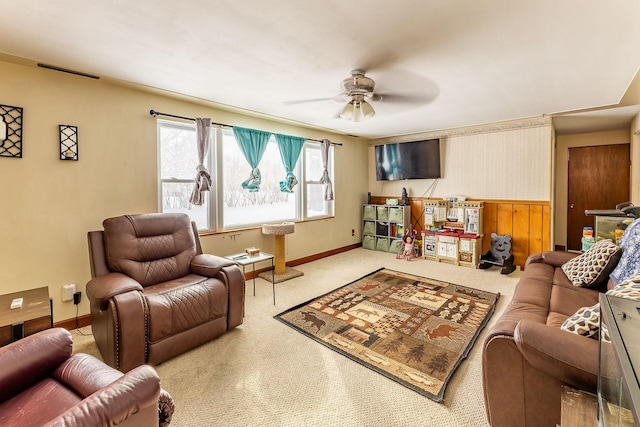 living room featuring ceiling fan, light colored carpet, and wood walls