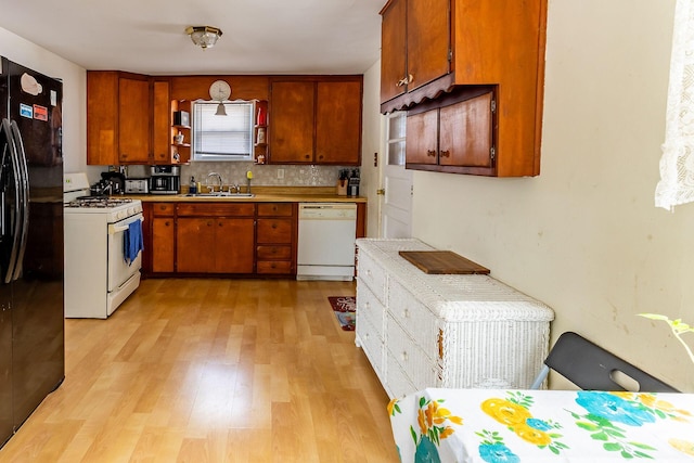 kitchen featuring sink, light hardwood / wood-style floors, backsplash, and white appliances