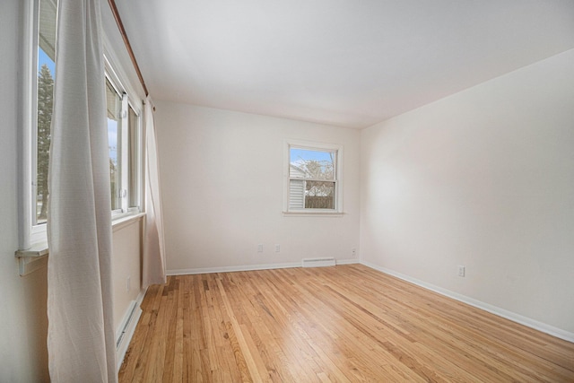 unfurnished room featuring baseboard heating and light hardwood / wood-style flooring