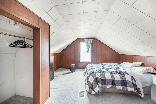 carpeted bedroom with vaulted ceiling and wood walls