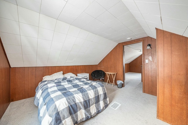 bedroom with light colored carpet, wood walls, and vaulted ceiling