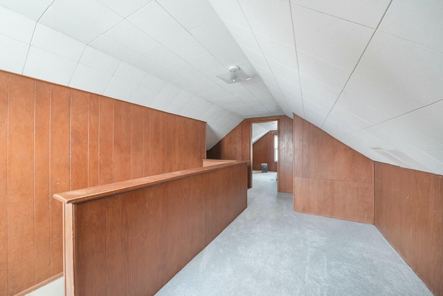 bonus room featuring light carpet, wood walls, and lofted ceiling