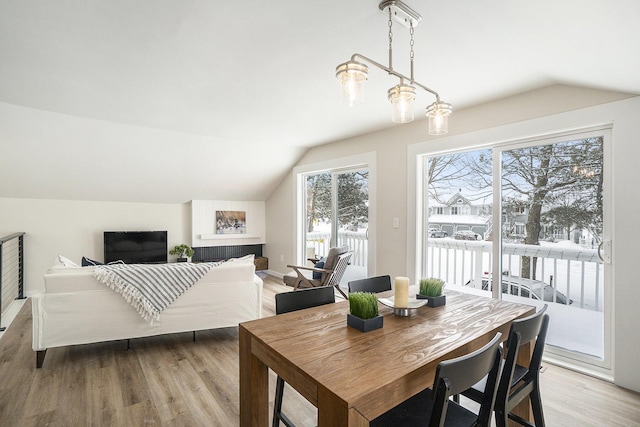 dining area with light wood-type flooring, vaulted ceiling, and plenty of natural light