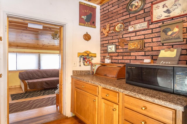 kitchen featuring brick wall, dark hardwood / wood-style flooring, and light stone countertops