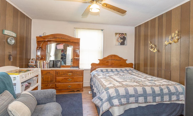 bedroom with ceiling fan, wood-type flooring, crown molding, and wooden walls