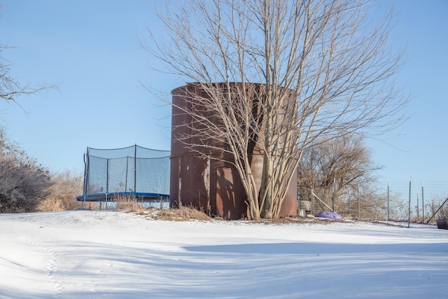 yard layered in snow with a trampoline