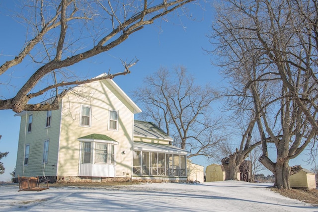 snow covered property featuring a sunroom