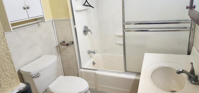 full bathroom featuring combined bath / shower with glass door, tile walls, sink, and toilet