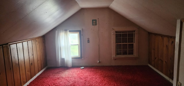 additional living space with carpet, lofted ceiling, and wood walls