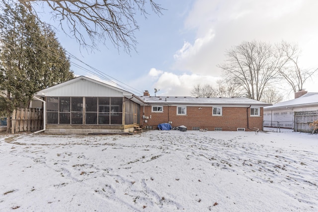 snow covered property featuring a sunroom