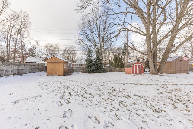 snowy yard featuring a storage shed