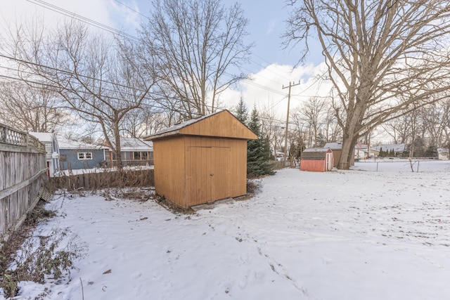 snowy yard featuring a storage shed