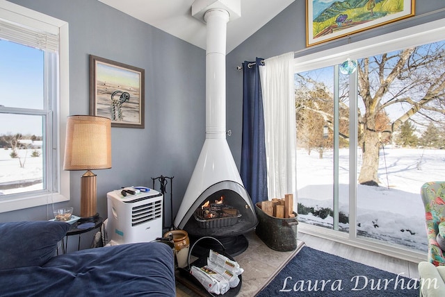 living area with hardwood / wood-style floors, vaulted ceiling, a wood stove, and a wealth of natural light